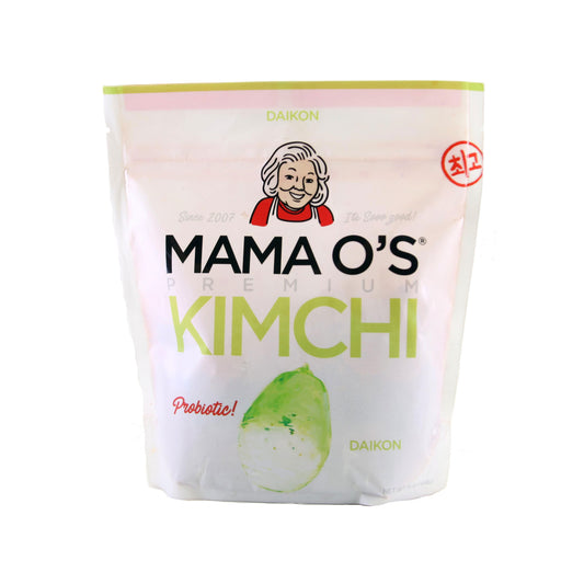 A white package of Mama Os Premium Daikon Kimchi features a cartoon woman’s face, Probiotic!, and a daikon radish illustration—highlighting bold flavor from authentic kimchi paste.
