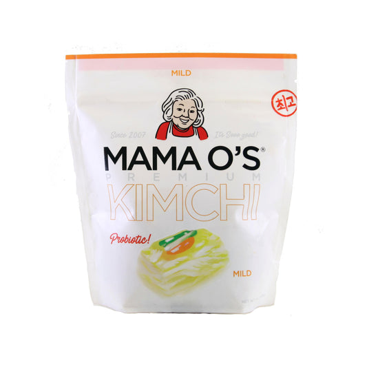 A white pouch of Mama O’s Premium White Kimchi displays “Probiotic!” in pink, features a woman’s face at the top, and shows kimchi with peppers. The vegan package is labeled by Mama O’s Premium Kimchi.