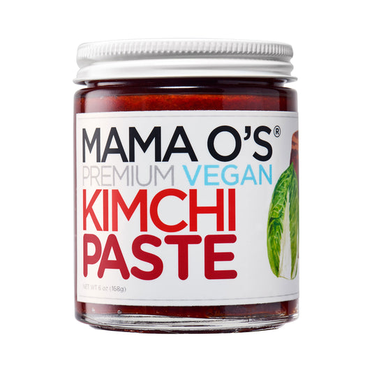 A jar of Mama Os Vegan Kimchi Paste by Mama Os Premium Kimchi, with a white lid and label showing bold red and black text plus napa cabbage. The all natural paste is made with Korean chili peppers.