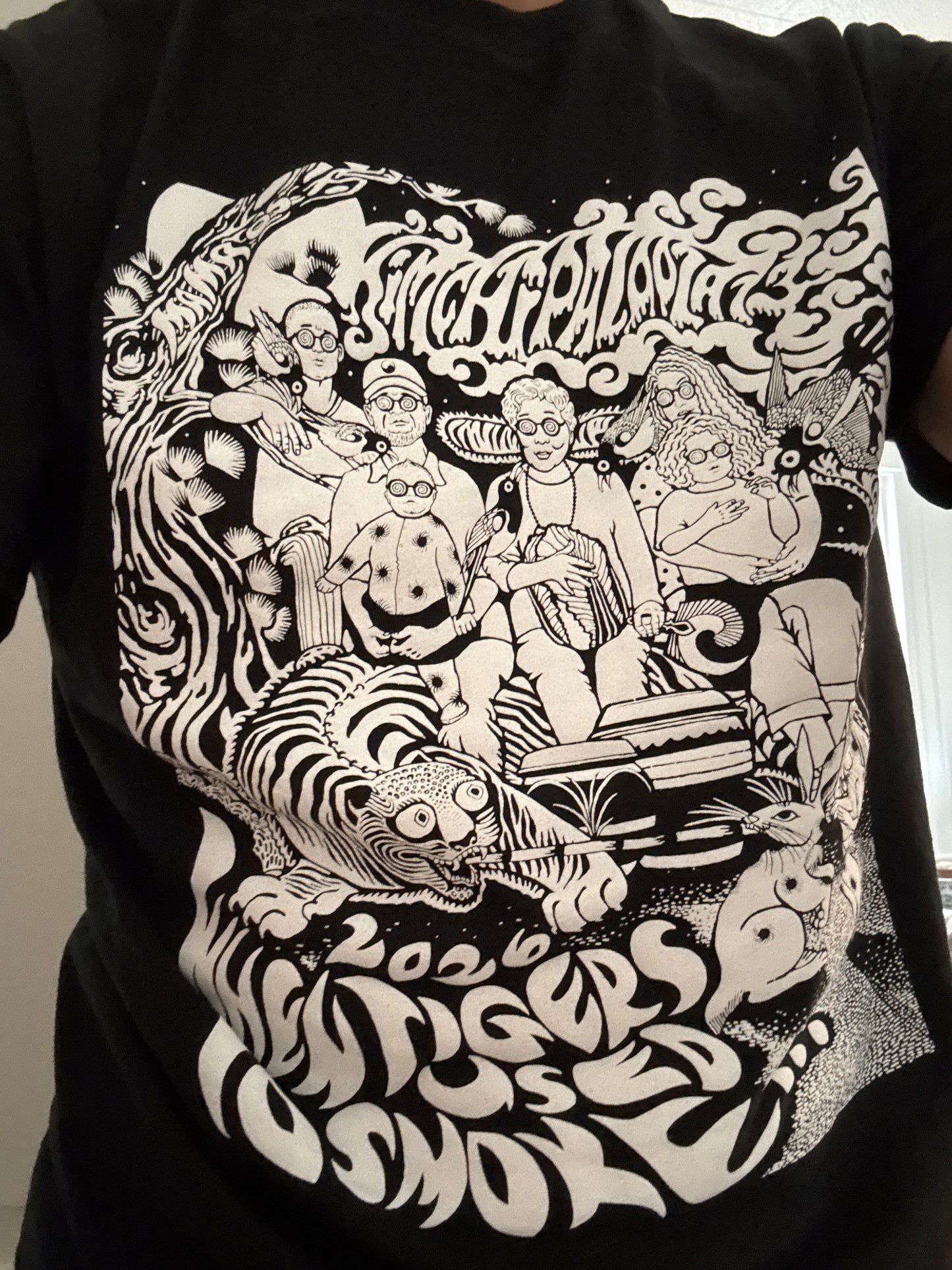 Sure! Here’s a rewritten version using your product data: The KIMCHIPALOOZA 13 TSHIRT by Mama O’s Premium Kimchi is a black tee featuring psychedelic white artwork with four people, a tiger, books, and swirling smoke. Created by Jillian Leedy for Kimchipalooza 13, the design includes the distorted text “2020 When Tigers Used To Smoke.”.