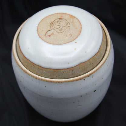 The Custom handmade Mama Os Homemade Kimchi Kit by Mama Os Premium Kimchi features a handcrafted ceramic jar with a white lid and engraved smiling face, perfect for kimchi making, set on a black background.
